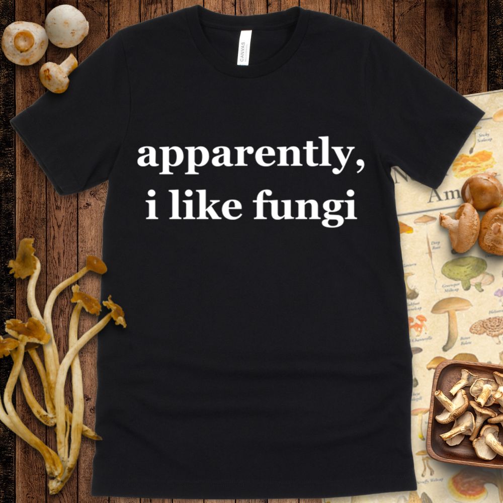 Black T-shirt with white serif text that reads “apparently, i like fungi” in a minimalist style.