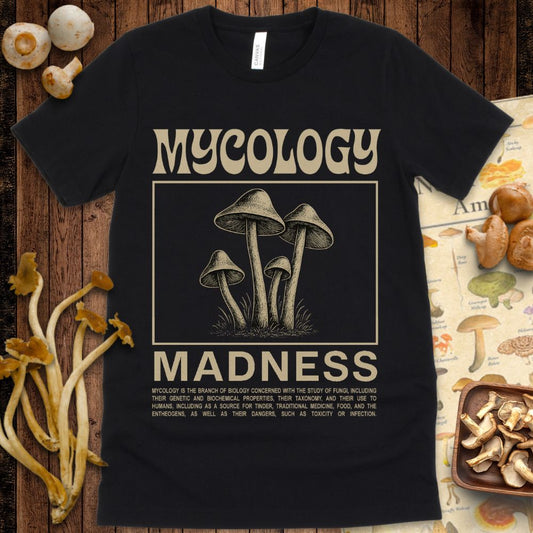 Vintage-style graphic T-shirt design featuring detailed mushrooms with the text “Mycology Madness” and a description of mycology.