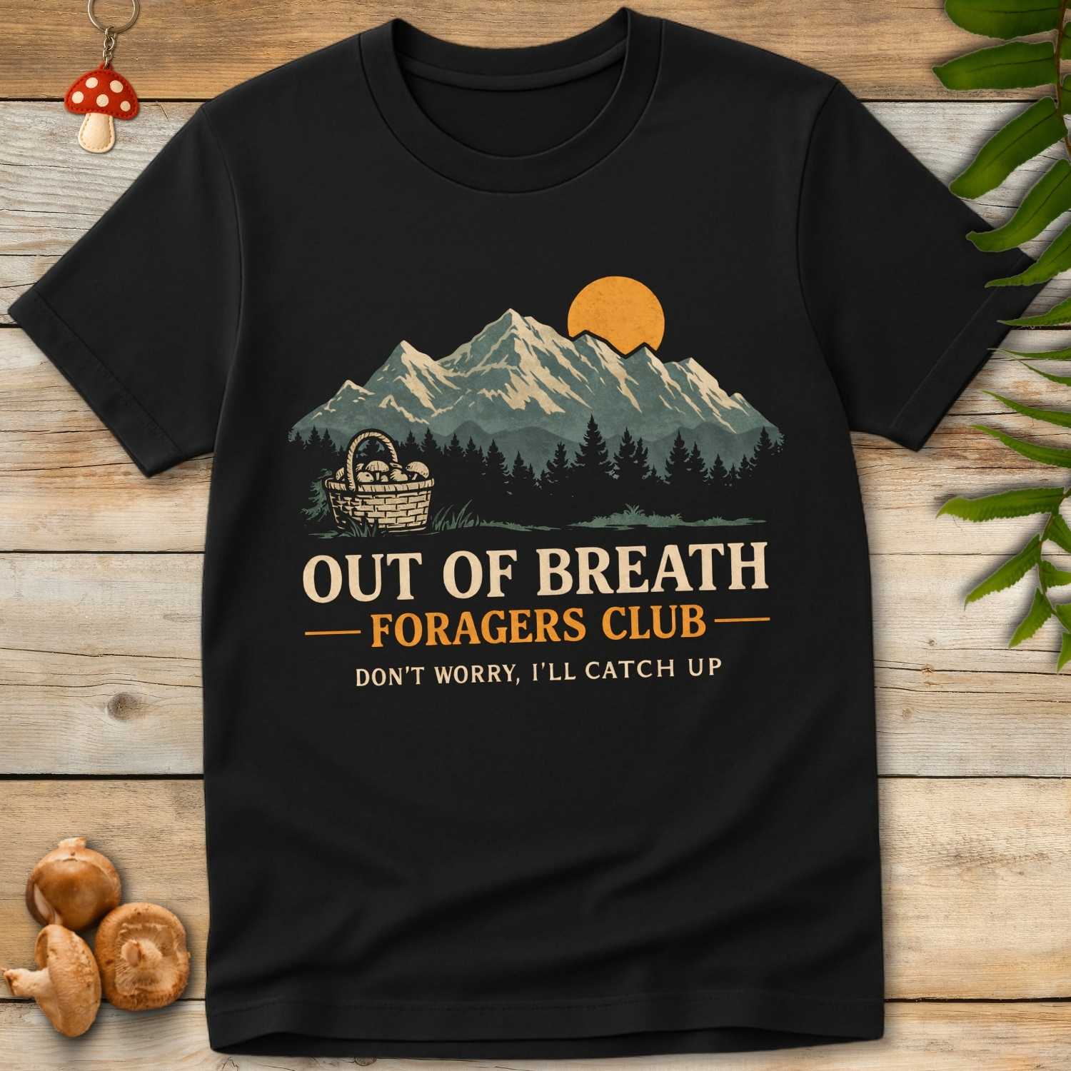 T-shirt design with mountain sunset, pine forest, and a mushroom basket featuring the text “Out of Breath Foragers Club – Don’t Worry, I’ll Catch Up”