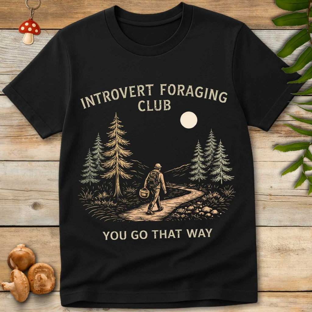 Vintage-style t-shirt design of a solo hiker in the woods carrying a basket, with the phrase “Introvert Foraging Club – You Go That Way”