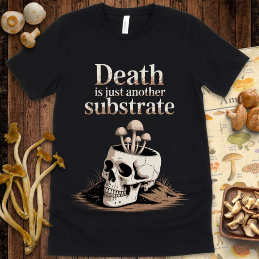 Illustrated t-shirt design showing mushrooms growing from a cracked human skull with the text "Death is just another substrate" above