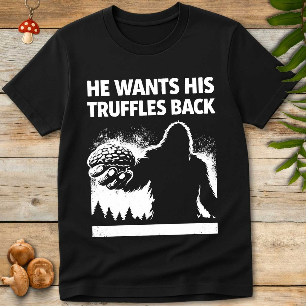 white illustration of Bigfoot holding a truffle with bold text reading “He Wants His Truffles Back” above a forest silhouette