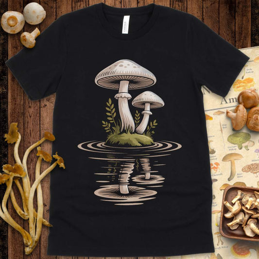 Two white mushrooms on a mossy mound floating in rippling water on a graphic tee