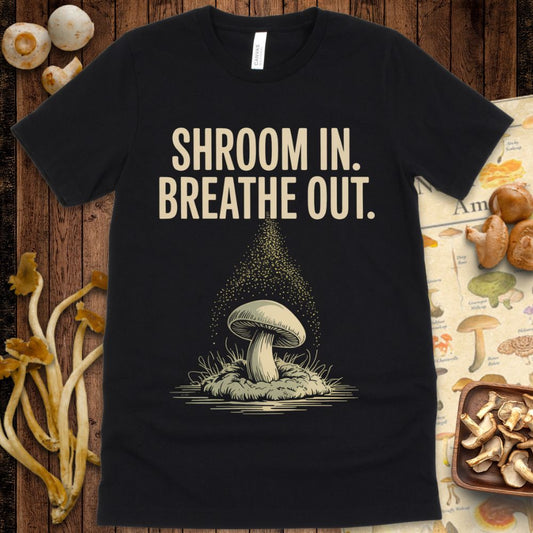 Mushroom releasing spores with the text “Shroom In. Breathe Out.” in a meditative, nature-inspired design