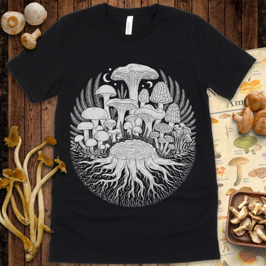 Intricate black and white illustration of mushrooms growing from a tree stump with roots, ferns, and moons in a circular forest-inspired design