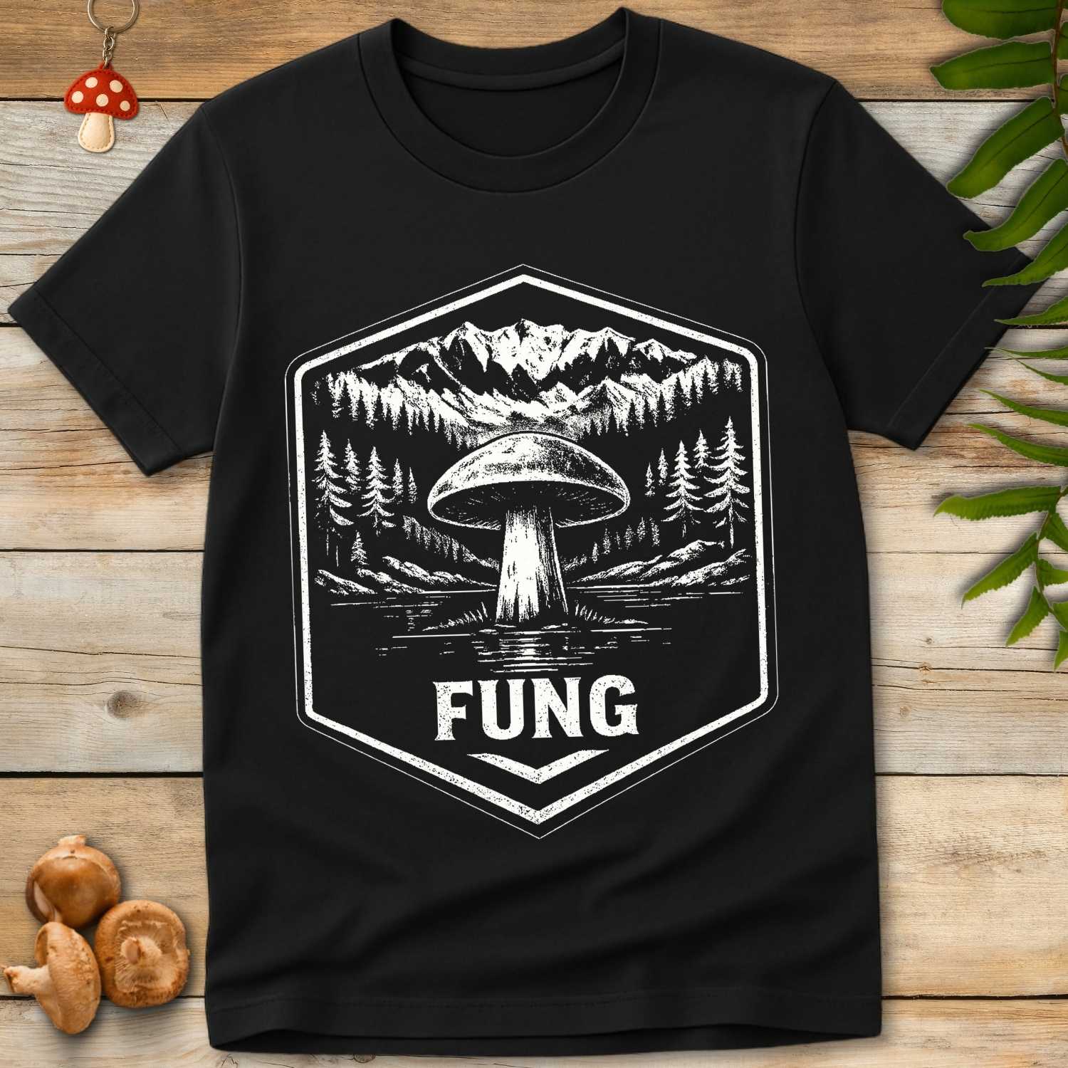 Vintage badge-style mushroom illustration by a lake and mountains with the word “FUNG” as a playful singular version of fungi.