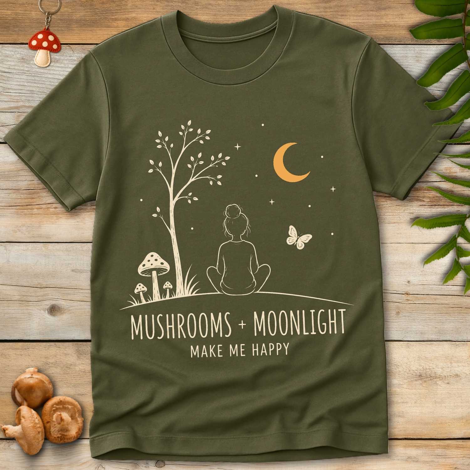 Girl Moonlight Tee featuring a seated girl under a crescent moon with woodland mushrooms, stars, butterfly, and cozy forest cottagecore artwork.