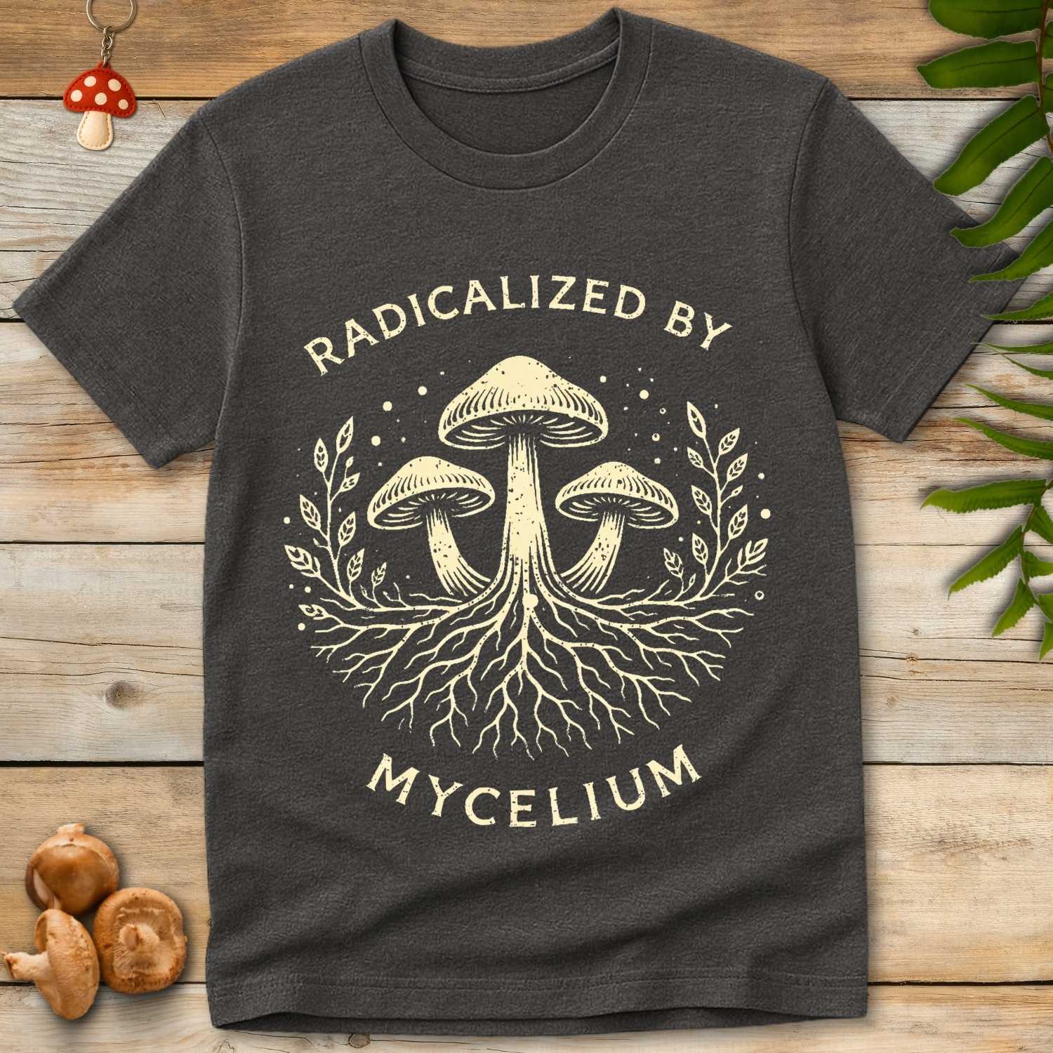 Radical Mycelium t-shirt design with three mushrooms, mycelium roots, and vintage botanical elements in cream on black