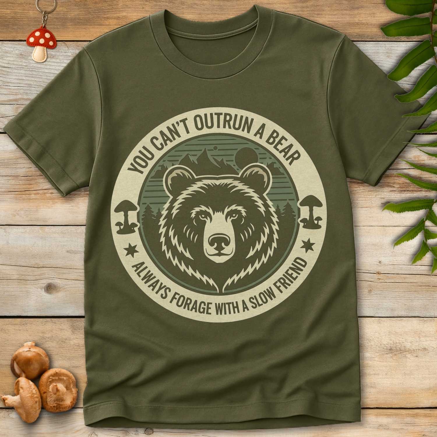 Circular design with a grizzly bear, mushrooms, and forest background, featuring the text “You Can’t Outrun a Bear – Always Forage with a Slow Friend.”