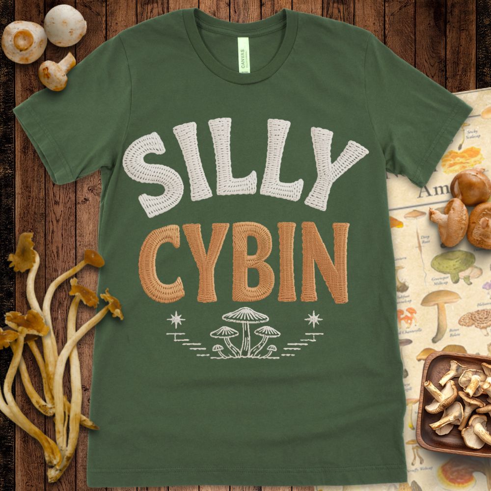 Textured faux-embroidered “Silly Cybin” text in cream and brown with embroidered mushroom illustration below on black background.