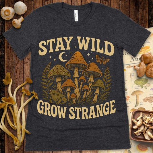 Retro-style illustration of mushrooms, a frog, moth, crescent moon, and stars with the phrase “Stay Wild, Grow Strange” in bold vintage lettering.