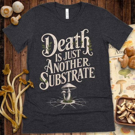 T-shirt design with the phrase “Death Is Just Another Substrate,” featuring vintage lettering, leafy accents, and mushrooms growing from cracked ground