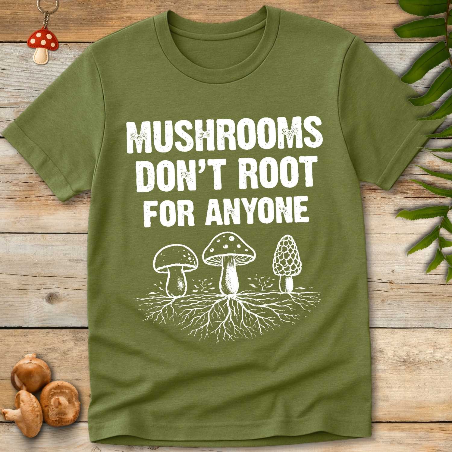 Green T-shirt with white text “Mushrooms Don’t Root for Anyone” above mushroom illustrations with visible mycelial networks