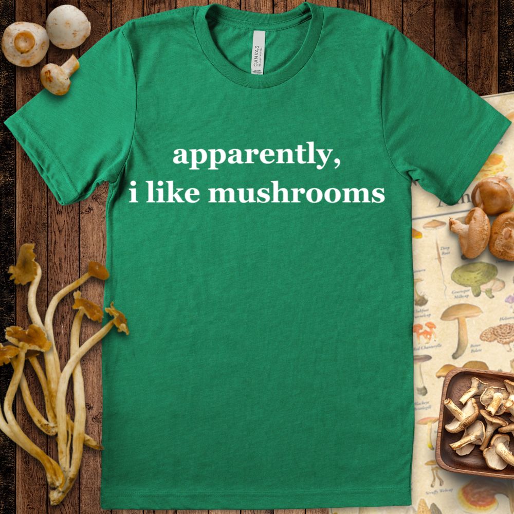 Minimalist green T-shirt design with white serif text that reads “apparently, i like mushrooms.”