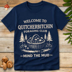 Vintage graphic t-shirt design with a basket full of mushrooms, pine trees, and bold text saying “Quitcherbitchin Foraging Club – Mind the Mud”