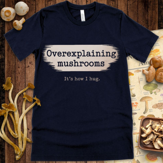 T-shirt design with typewriter-style text that reads "Overexplaining mushrooms – It's how I hug" on a beige brushstroke background