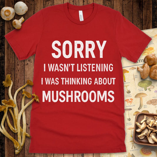 Black T-shirt design with distressed white text that says "Sorry I wasn't listening, I was thinking about mushrooms"